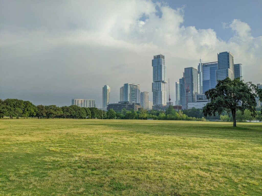 Clouds building over the downtown Austin skyline, seen across the open lawn at Auditorium Shores