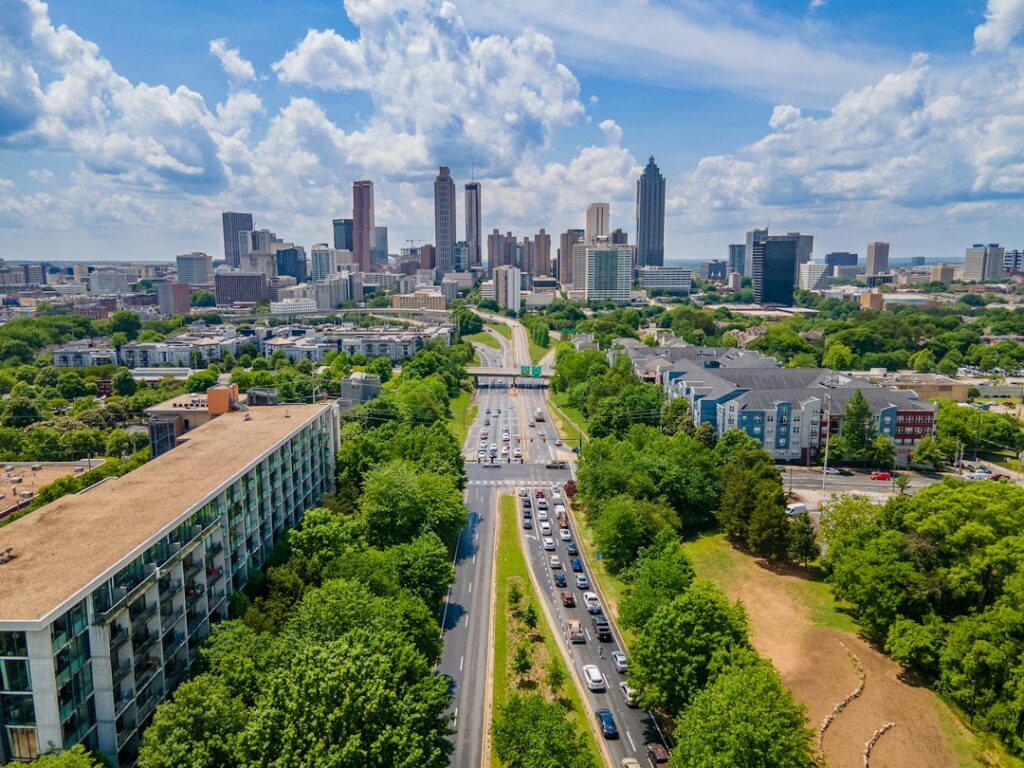 Aerial view of apartment buildings and a tree-lined parkway leading to the downtown Atlanta skyline